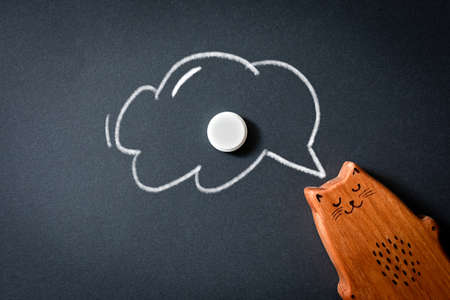 a toy in the form of a wooden cat with a dream cloud and a tablet. The concept of dependence on sleeping pills, pills, drugs, a drug for sleep or insomnia.の写真素材