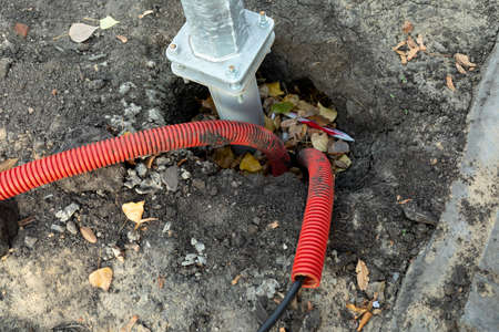 Two red plastic corrugated pipes with wires for bringing electricity to the construction site. Metal...