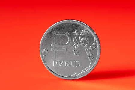 Coin one Russian ruble on a red background. The concept of crisis during sanctions, currency exchange, gas purchases for rubles, exchange rate. Close up, copy spaceの写真素材