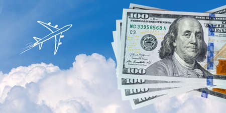 Naive children drawing of airplane above clouds next to US hundred dollar bills. Expensive fuel for flights or saving money for vacation conceptの写真素材