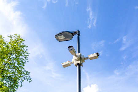 A modern lamppost and 3 surveillance cameras mounted in different directions in a public park....