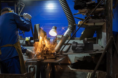 Metal parts are ground with an electric grinding machine. Sparks flying from metal cutting process