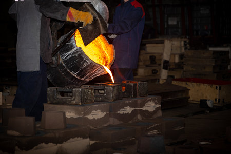 Pouring liquid high temperature metal from the vat into sand mold. Foundry process to manufacture...