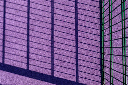 Purple floor covering made of recycled materials. Special rubber coating for children's playground or sports with long shadows of the fence. Protective floor covering with rubber granules.の写真素材
