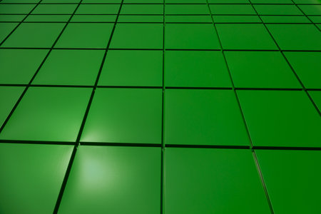 a fragment of a green aluminum ventilated facade with aa drainpipe on a blue sky backgroundの写真素材