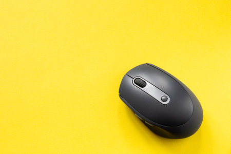 Black computer mouse on yellow background. Wireless optical PC mouse. Wireless technology. Copy spaceの写真素材