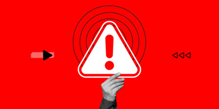 Attention concept. A hand holds a danger warning sign with an exclamation mark on a red background....