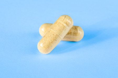 two pills with a transparent shell and yellow powder inside on a blue background for visualizing content on medical and pharmaceutical websites, presentations, advertising. Copy spaceの写真素材