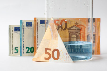 Economy. Increasing the cost of water is a concept. A jar with a small amount of water next to the euro banknotes.の写真素材