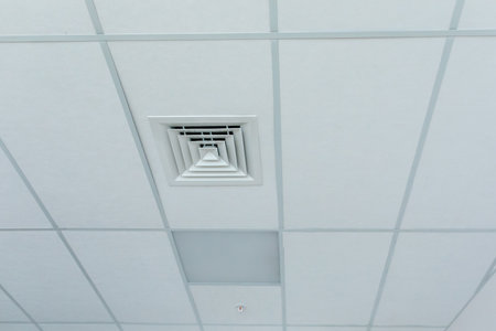 Suspended ceiling with square halogen spots lamps and supply and exhaust ventilation system in room in commercial room, office or warehouse. Stretch ceiling white. Stretch ceiling white.の写真素材