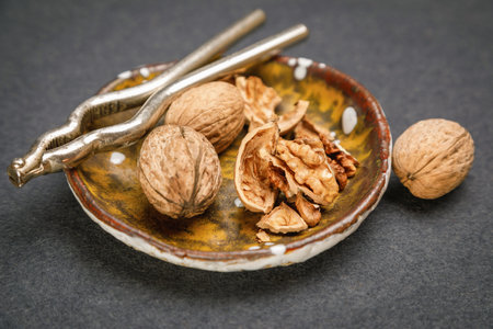 A decorative plate holds whole walnuts and broken walnut shells, accompanied by a classic...