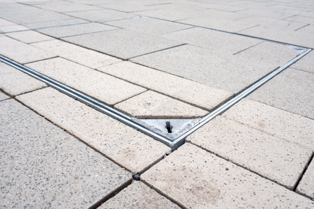 Modern geometric paver sidewalk with concealed square manhole for utilities. Improvement of...
