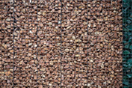Gabion wall filled with brown stones and metal mesh texture. Great for architectural visuals,...