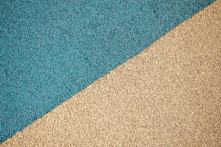 Granulated sports and playground surface in blue and beige colors, textured material pattern. Real...