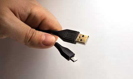 Hand holding Micro USB cable isolated on white backgroundの写真素材