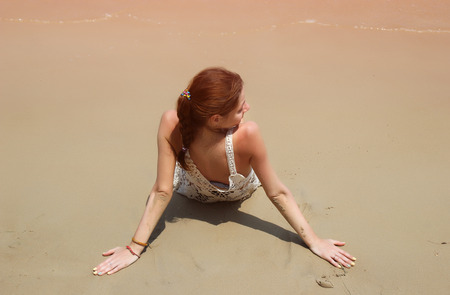 Beautiful tanned brunette in white bikini sitting on the beachの写真素材