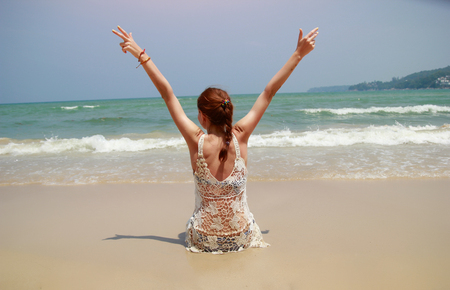 Beautiful tanned brunette in white bikini sitting on the beachの写真素材