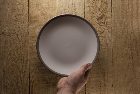 Hand hold plate on wood surfaceの写真素材