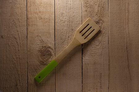 Spatula on the wooden background. Green handleの写真素材