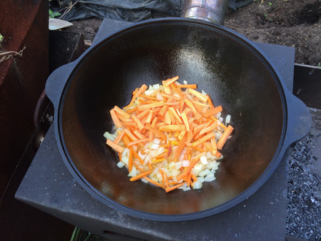 Preparation of pilaf on fire. Tourist bowler with food on bonfire, cooking in the hike, outdoor activities.の写真素材