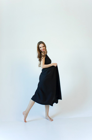 Young woman in long black dress isolated on white background.の写真素材