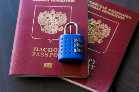 Blue lock lying on two red passports on a wooden background, close-up.の写真素材