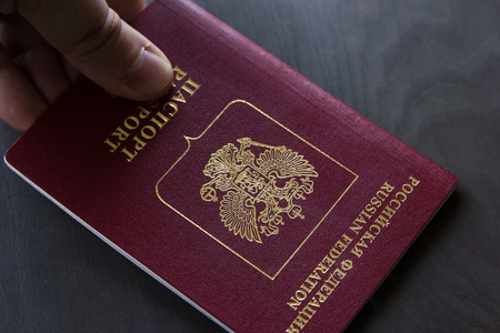 Red Russian passport on the wooden surface with captions Passport and Russian Federation in Cyrillic alphabet.の写真素材