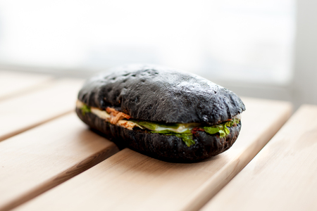 Black sandwich baguette on wooden surface. Closeup. Selective focus.の写真素材