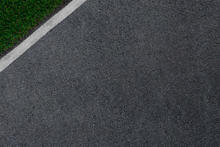 the asphalt which is smoothly passing to a white border and a green grass.の写真素材
