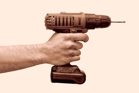 Hand holds cordless electric screwdriver with bit for screws isolated on white background.の写真素材