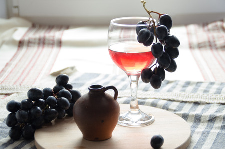 A glass of red wine and a branch of grapes
