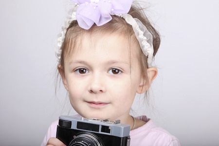 Young girl holding an old vintage camera against white backgroundの写真素材