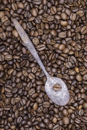 Roasted grains of coffee and old spoon background closeupの写真素材