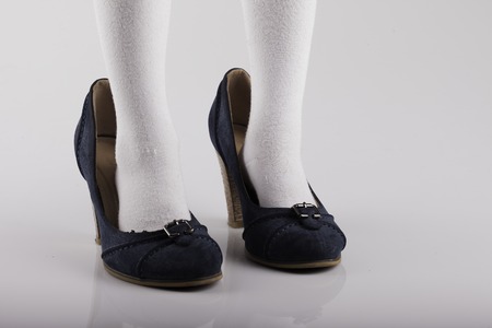 of the child's feet in large female shoes on a white backgroundの写真素材