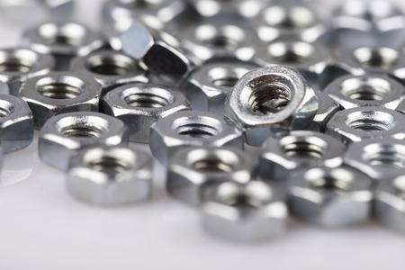 abstract background metal nuts close up isolated on whiteの写真素材