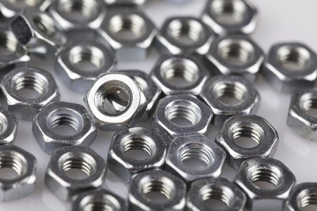 abstract background metal nuts close up isolated on whiteの写真素材