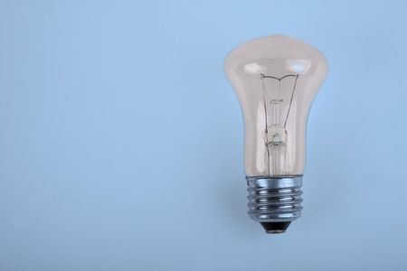 the traditional incandescent light bulb on blue backgroundの写真素材