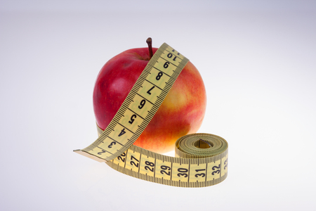 Red Apple and tape measure closeup on white backgroundの写真素材
