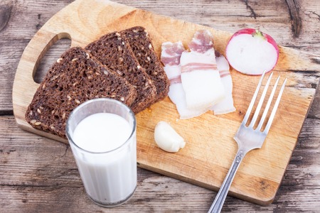 dinner on a wooden board with glass of milk on table still life