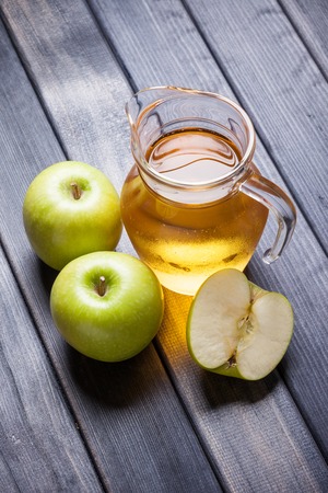 Apple juice in pitcher on table, vertical photo still lifeの写真素材