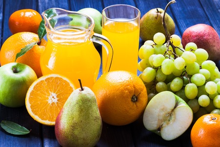 Fruit and juice still life, jug, glass, grape, pear, Apple oranges on wood backgroundの写真素材