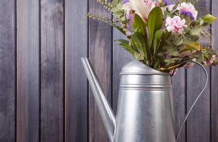 horizontal still life flowers in watering in grunge can dark wooden backgroundの写真素材