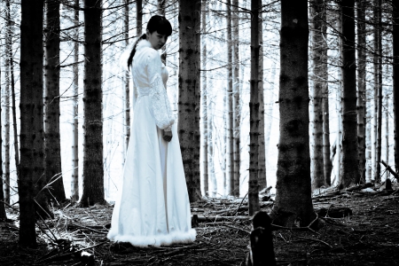 Woman with long black hair in white dress in the spooky dark forestの写真素材