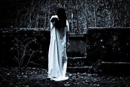 Woman with long black hair in white dress in the spooky dark forestの写真素材
