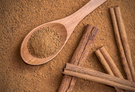 Spoon full of powdered cinnamon, with cinnamon sticksの写真素材
