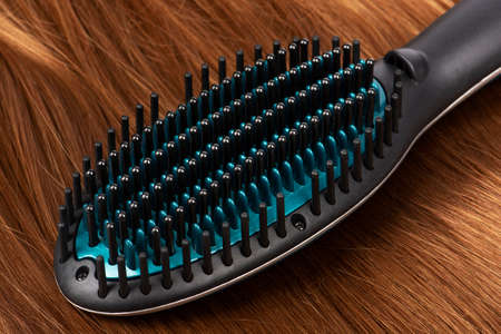 Electric hair straightening brush on red hair