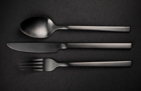 Black Silverware Set. Fork, knife and spoon on black background