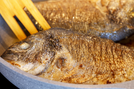 Fried Dorado fish in a frying pan. Close-up. の写真素材