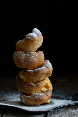 Slide of Yorkshire puddings on black plate with powdered sugar on black natural wooden background.の写真素材