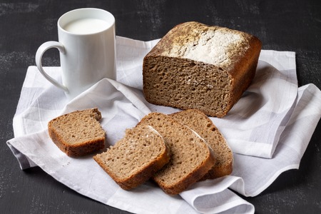Form rye-wheat bread, sliced, and a mug of milk.